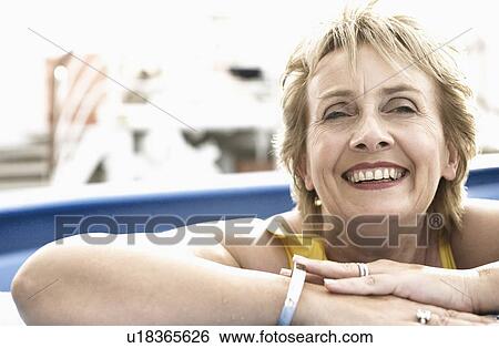 Stock Photograph - Portrait of a mature woman smiling in a swimming pool. Fotosearch
