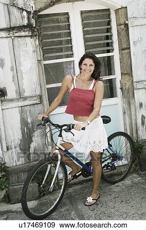Portrait of a mid adult woman riding a bicycle and smiling View Large Photo Image Stock Photo - Portrait of a mid adult woman riding a bicycle and smiling. Fotosearch