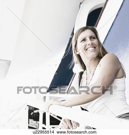 Side profile of a mid adult woman standing on the staircase of a cruise ship and smiling View Large Photo Image Picture - Side profile of a mid adult woman standing on the staircase of a cruise ship and smiling. Fotosearch