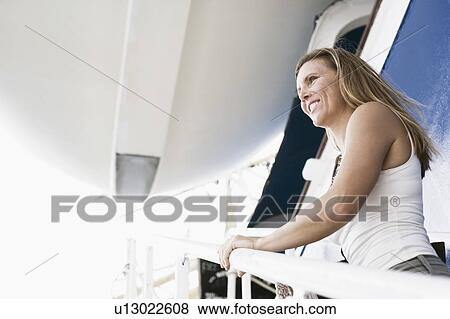 Side profile of a mid adult woman standing on the staircase of a cruise ship and smiling View Large Photo Image Stock Photo - Side profile of a mid adult woman standing on the staircase of a cruise ship and smiling. Fotosearch