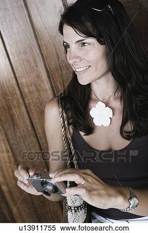 Close-up of a mid adult woman holding a digital camera View Large Photo Image Stock Photography - Close-up of a mid adult woman holding a digital camera. Fotosearch