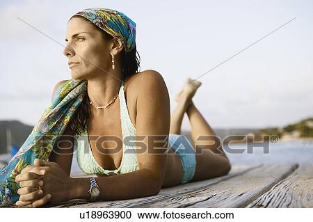 Close-up of a mid adult woman lying on a pier View Large Photo Image Stock Image - Close-up of a mid adult woman lying on a pier. Fotosearch