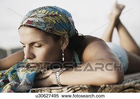 Close-up of a mid adult woman lying on a pier View Large Photo Image Stock Photography - Close-up of a mid adult woman lying on a pier. Fotosearch