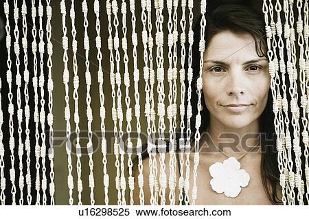 Close-up of a mid adult woman peeking through a beaded curtain View Large Photo Image Stock Photography - Close-up of a mid adult woman peeking through a beaded curtain. Fotosearch
