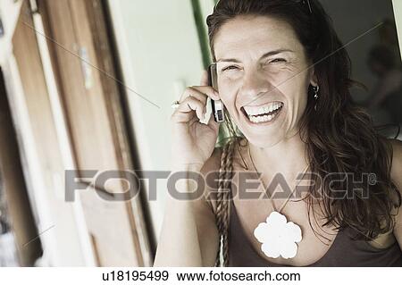 Stock Photo - Close-up of a mid adult woman talking on a mobile phone and smiling. Fotosearch