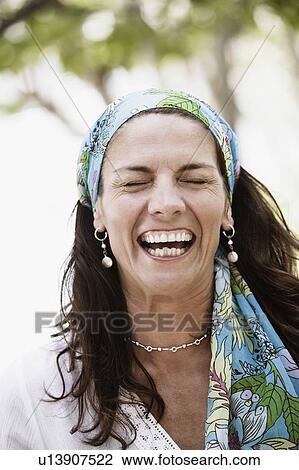 Stock Image - Close-up of a mid adult woman wearing a headscarf and laughing. Fotosearch