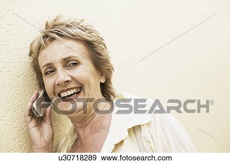 Mature woman talking on a mobile phone and smiling View Large Photo Image Stock Photo - Mature woman talking on a mobile phone and smiling. Fotosearch