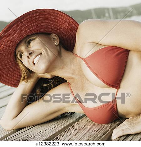 Mid adult woman lying on a pier and smiling View Large Photo Image Stock Image - Mid adult woman lying on a pier and smiling. Fotosearch