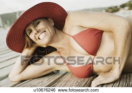 Stock Photograph - Mid adult woman lying on a pier and smiling. Fotosearch