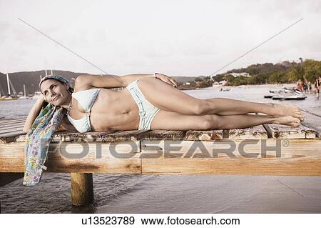 Mid adult woman lying on a pier View Large Photo Image Stock Photo - Mid adult woman lying on a pier. Fotosearch
