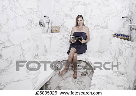 Mid adult woman sitting in the bathroom and reading a magazine View Large Photo Image Stock Photograph - Mid adult woman sitting in the bathroom and reading a magazine. Fotosearch