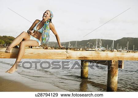 Mid adult woman sitting on a pier and smiling View Large Photo Image Stock Photo - Mid adult woman sitting on a pier and smiling. Fotosearch