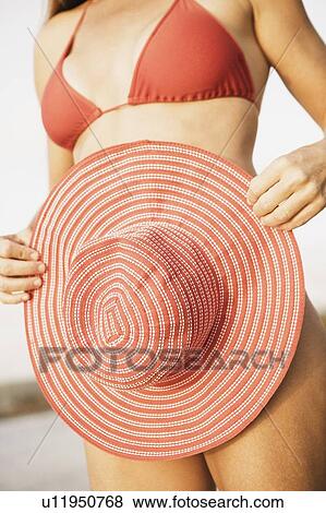 Mid section view of a woman holding a hat View Large Photo Image Stock Photo - Mid section view of a woman holding a hat. Fotosearch