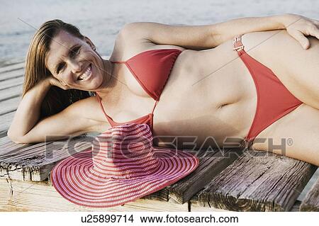 Portrait of a mid adult woman lying on a pier and smiling View Large Photo Image Picture - Portrait of a mid adult woman lying on a pier and smiling. Fotosearch