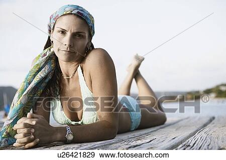 Stock Photo - Portrait of a mid adult woman lying on a pier. Fotosearch