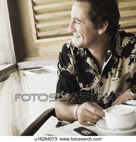 Stock Image - Close-up of a mid adult man holding a cup and smiling. Fotosearch