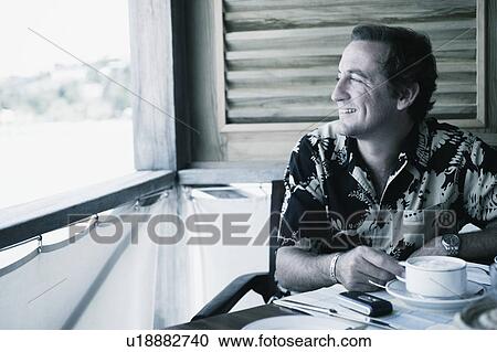 Close-up of a mid adult man holding a cup of coffee in a restaurant View Large Photo Image Stock Image - Close-up of a mid adult man holding a cup of coffee in a restaurant. Fotosearch