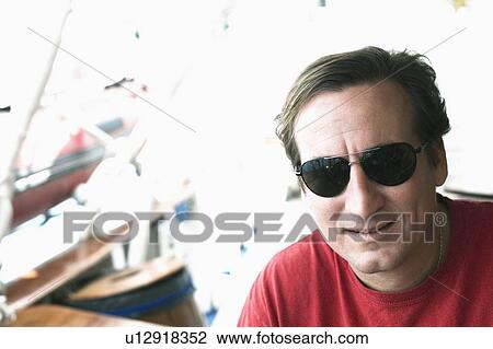 Stock Image - Close-up of a mid adult man wearing sunglasses. Fotosearch