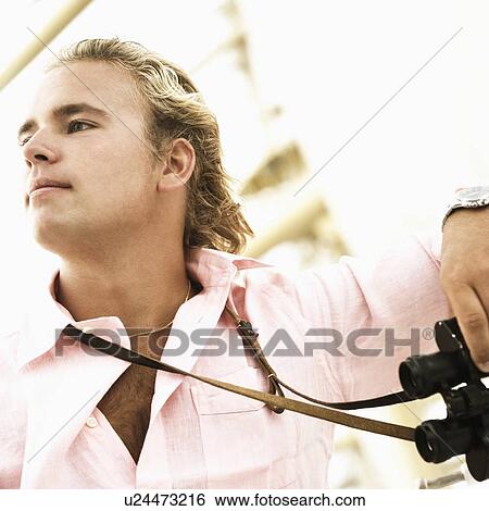 Stock Photograph - Close-up of a young man holding binoculars. Fotosearch