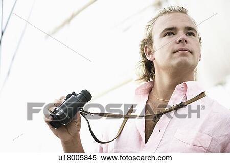 Close-up of a young man holding binoculars View Large Photo Image Stock Photography - Close-up of a young man holding binoculars. Fotosearch