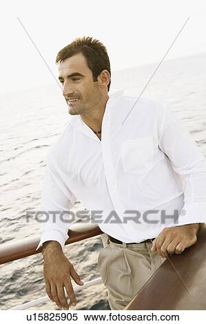 Mid adult man leaning against the railing of a ship View Large Photo Image Stock Photography - Mid adult man leaning against the railing of a ship. Fotosearch