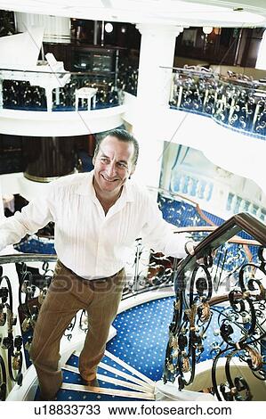Mid adult man moving up on a staircase and smiling in a ship View Large Photo Image Stock Image - Mid adult man moving up on a staircase and smiling in a ship. Fotosearch