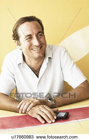Mid adult man sitting in a restaurant and smiling View Large Photo Image Stock Image - Mid adult man sitting in a restaurant and smiling. Fotosearch