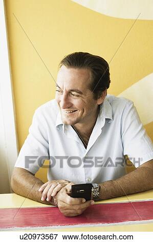 Stock Photo - Mid adult man sitting in a restaurant. Fotosearch