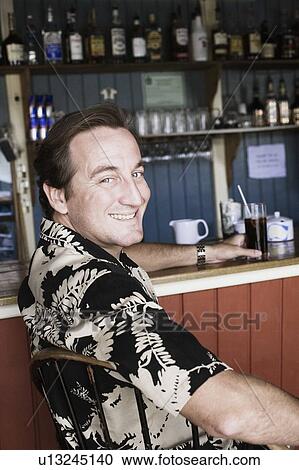 Stock Image - Portrait of a mid adult man holding a glass of drink. Fotosearch