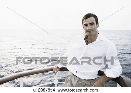 Portrait of a mid adult man leaning against the railing of a boat View Large Photo Image Picture - Portrait of a mid adult man leaning against the railing of a boat. Fotosearch