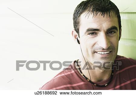 Portrait of a mid adult man listening to earbuds and smiling View Large Photo Image Stock Image - Portrait of a mid adult man listening to earbuds and smiling. Fotosearch