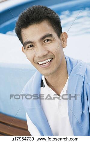 Portrait of a young man smiling and carrying a jacket over his shoulder View Large Photo Image Stock Photo - Portrait of a young man smiling and carrying a jacket over his shoulder. Fotosearch