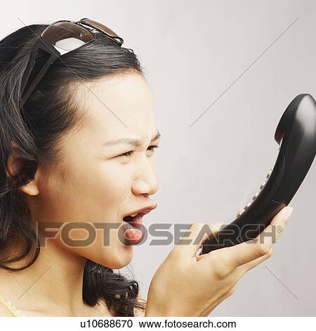 Side profile of a young woman shouting on the phone View Large Photo Image Stock Image - Side profile of a young woman shouting on the phone. Fotosearch