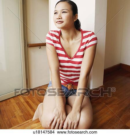 Young woman kneeling on a hardwood floor View Large Photo Image Picture - Young woman kneeling on a hardwood floor. Fotosearch