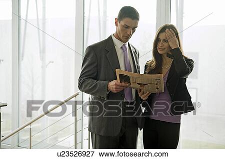 Stock Photo - Businessman and businesswoman looking at financial newspaper. Fotosearch