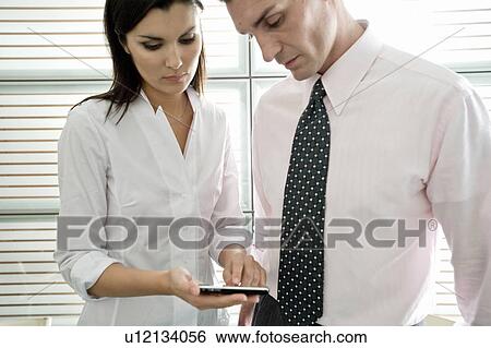 Businessman and businesswoman looking at calculator View Large Photo Image Stock Photograph - Businessman and businesswoman looking at calculator. Fotosearch