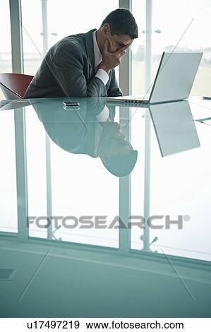 Businessman at laptop computer with his face in his hand View Large Photo Image Stock Photo - Businessman at laptop computer with his face in his hand. Fotosearch