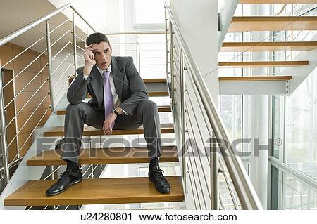 Businessman on office staircase holding his head View Large Photo Image Stock Image - Businessman on office staircase holding his head. Fotosearch