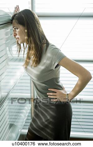 Stock Photograph - "Professional woman looking out window, worried". Fotosearch