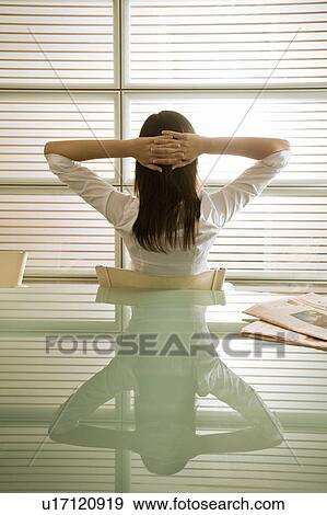 Back view of businesswoman in office with hands behind head View Large Photo Image Stock Photo - Back view of businesswoman in office with hands behind head. Fotosearch