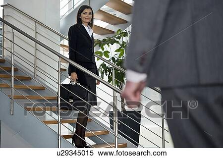 Businessman walking up to businesswoman on staircase View Large Photo Image Stock Photography - Businessman walking up to businesswoman on staircase. Fotosearch