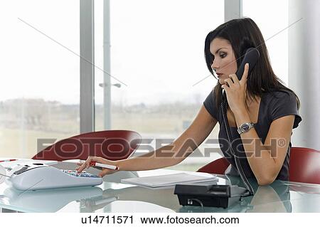 Professional woman on telephone using calculator View Large Photo Image Stock Image - Professional woman on telephone using calculator. Fotosearch