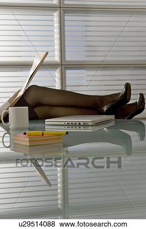 Professional woman reading newspaper with legs up on desk View Large Photo Image Stock Photo - Professional woman reading newspaper with legs up on desk. Fotosearch