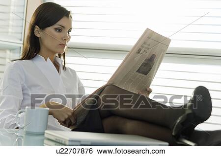 Professional woman reading newspaper with legs up on desk View Large Photo Image Stock Photograph - Professional woman reading newspaper with legs up on desk. Fotosearch