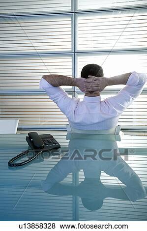 Back view of businessman in office with hands behind head View Large Photo Image Stock Photo - Back view of businessman in office with hands behind head. Fotosearch