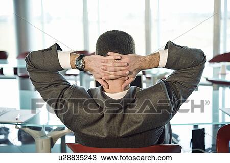 Businessman at conference table with hands behind head View Large Photo Image Stock Image - Businessman at conference table with hands behind head. Fotosearch