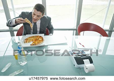 Businessman eating pizza at desk View Large Photo Image Stock Photography - Businessman eating pizza at desk. Fotosearch