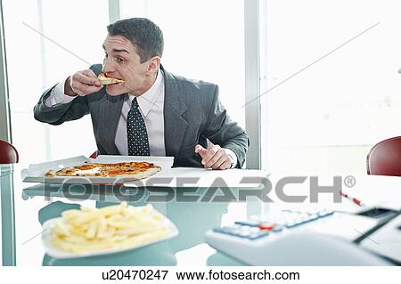 Businessman eating pizza with French fries at desk View Large Photo Image Stock Photo - Businessman eating pizza with French fries at desk. Fotosearch
