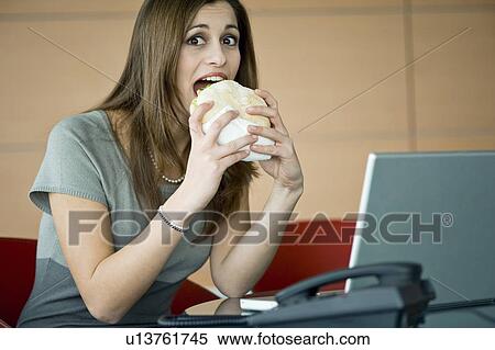 Businesswoman eating pita sandwich at desk View Large Photo Image Stock Photography - Businesswoman eating pita sandwich at desk. Fotosearch