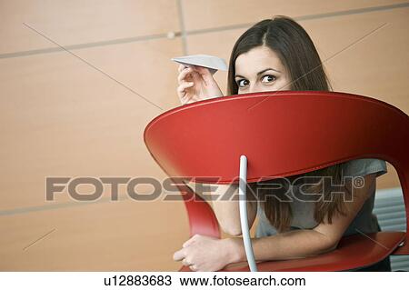 Businesswoman hiding behind chair with paper airplane View Large Photo Image Stock Image - Businesswoman hiding behind chair with paper airplane. Fotosearch